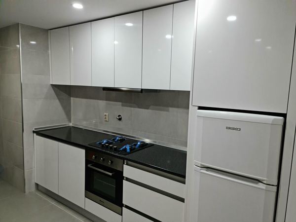 Cozinha branca brilhante com coluna para o frigorífico