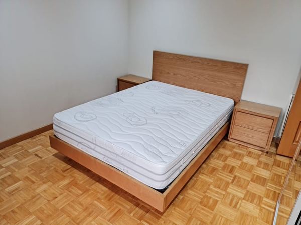 Cama de casal e mesas de cabeceira em madeira