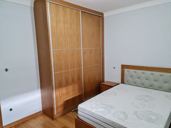 Roupeiro de correr em madeira e cama com cabeceira estofada