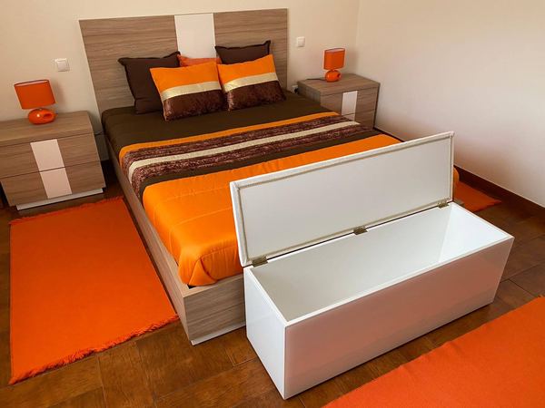 Quarto com cama, mesas de cabeceira e baú lacado branco