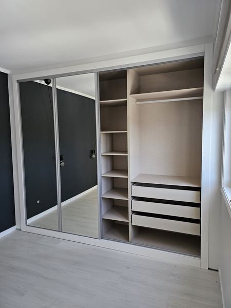 Roupeiro com portas de correr espelhadas e interior à vista